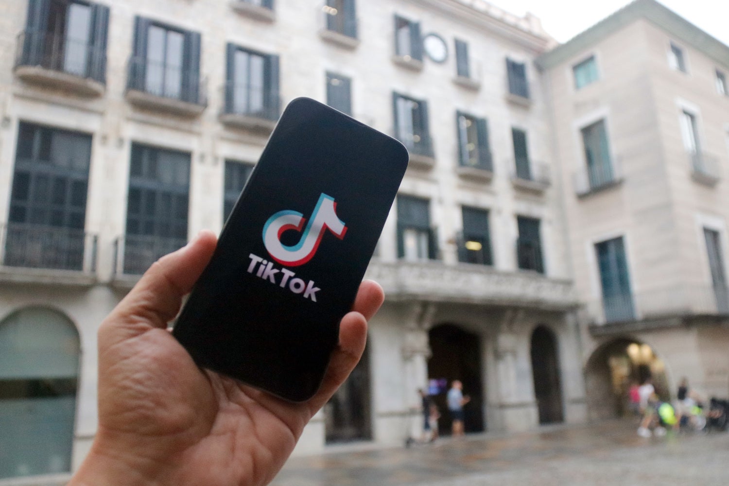 En primer terme, un m&ograve;bil amb el logotip d'una xarxa social; al fons, la fa&ccedil;ana de l'Ajuntament de Girona /  Xavier Pi - ACN